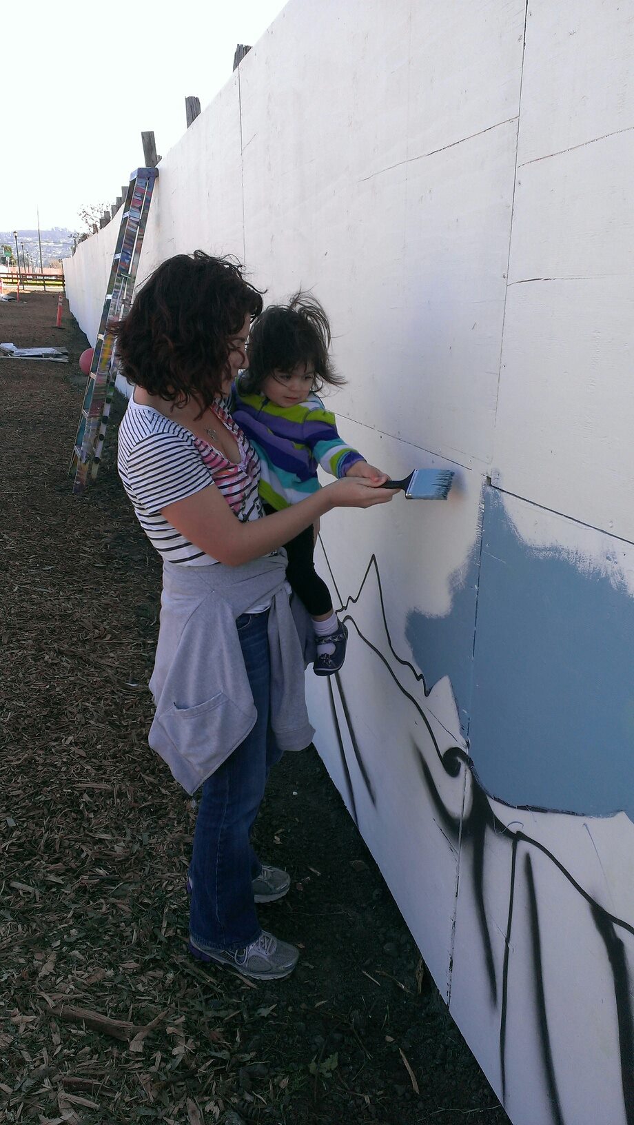 Calisi Rodríguez and her daughter help paint a mural at the community gardens on the Ohlone Greenway for the MLK Day of Service in Richmond, Calif. Courtesy Photo
