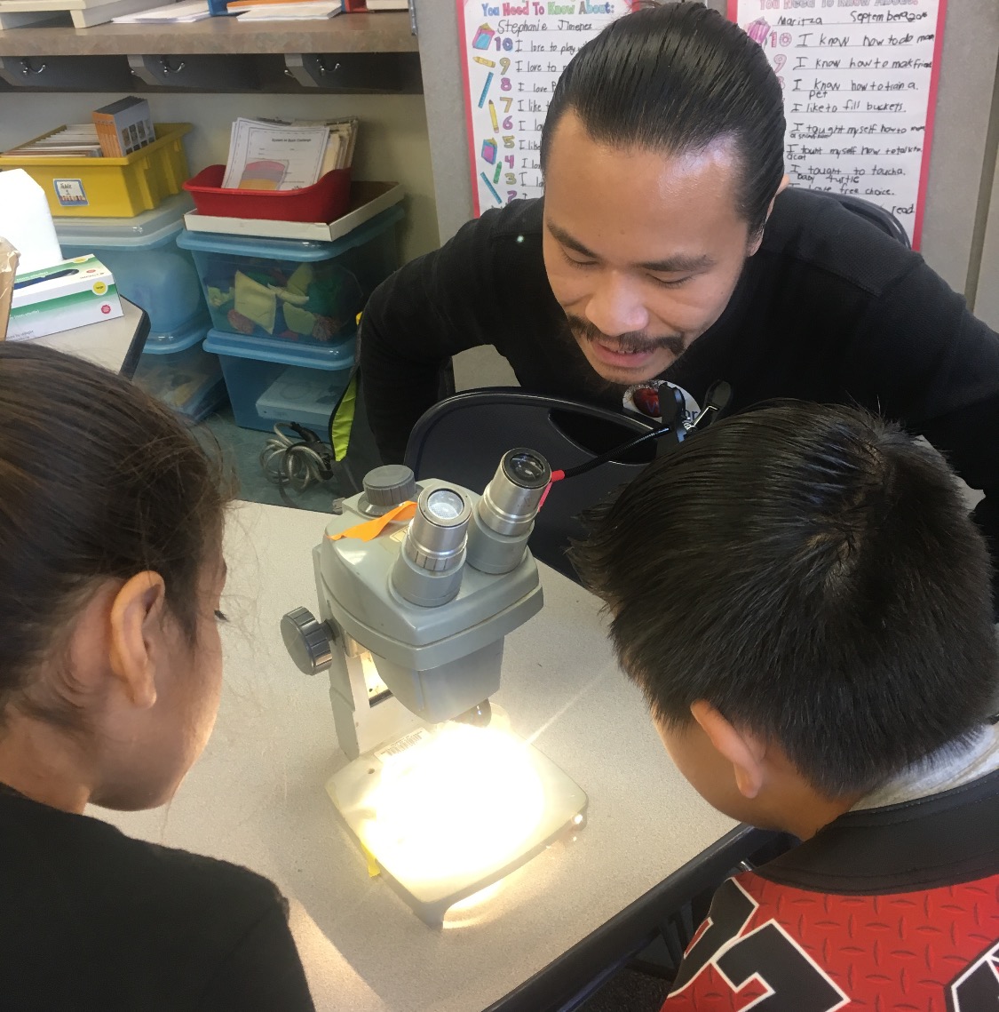 Young Scientist Program member Anthony Ho shows students how a microscope works. Photo courtesy of the Young Scientist Program 