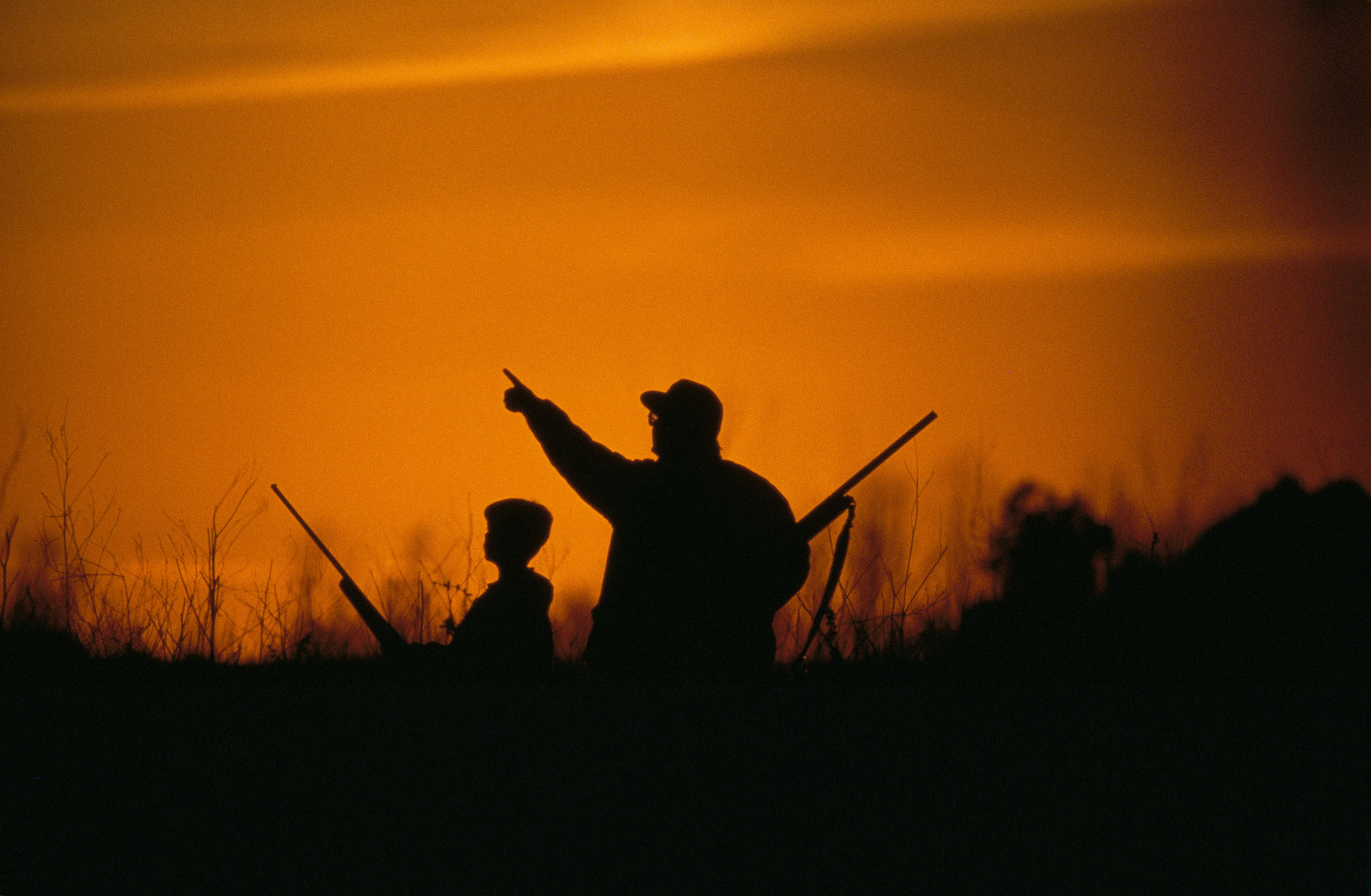 Image of two hunters against a sunset-colored sky. United States FIsh and Wildlife Service