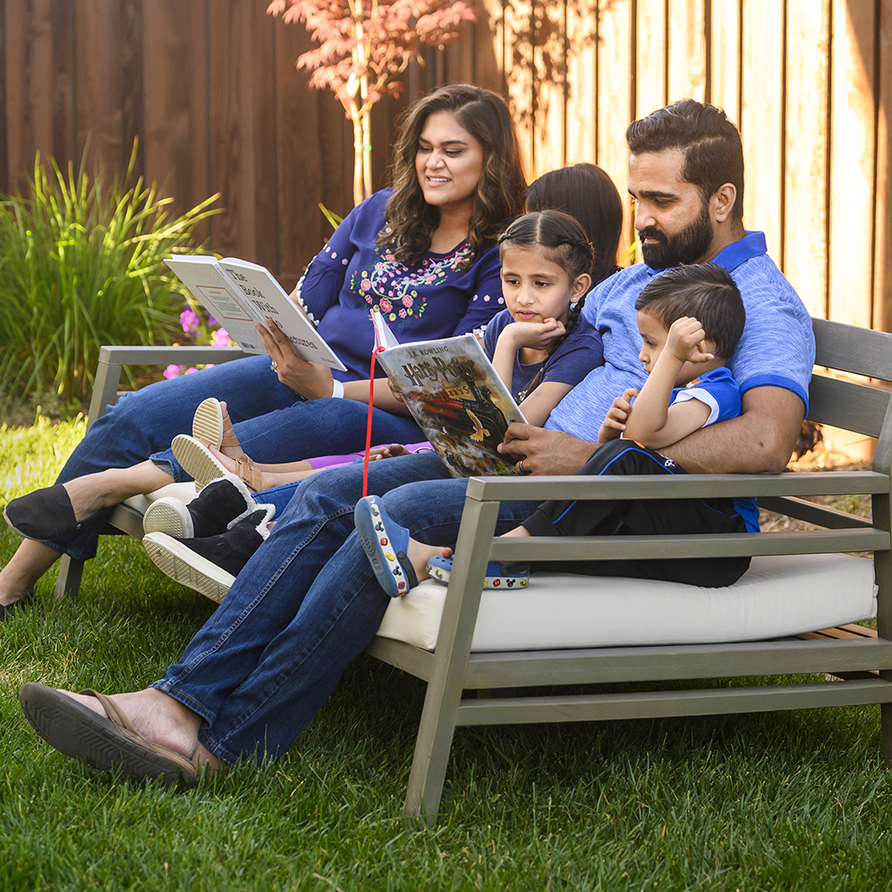 A family seated outside reading a book together