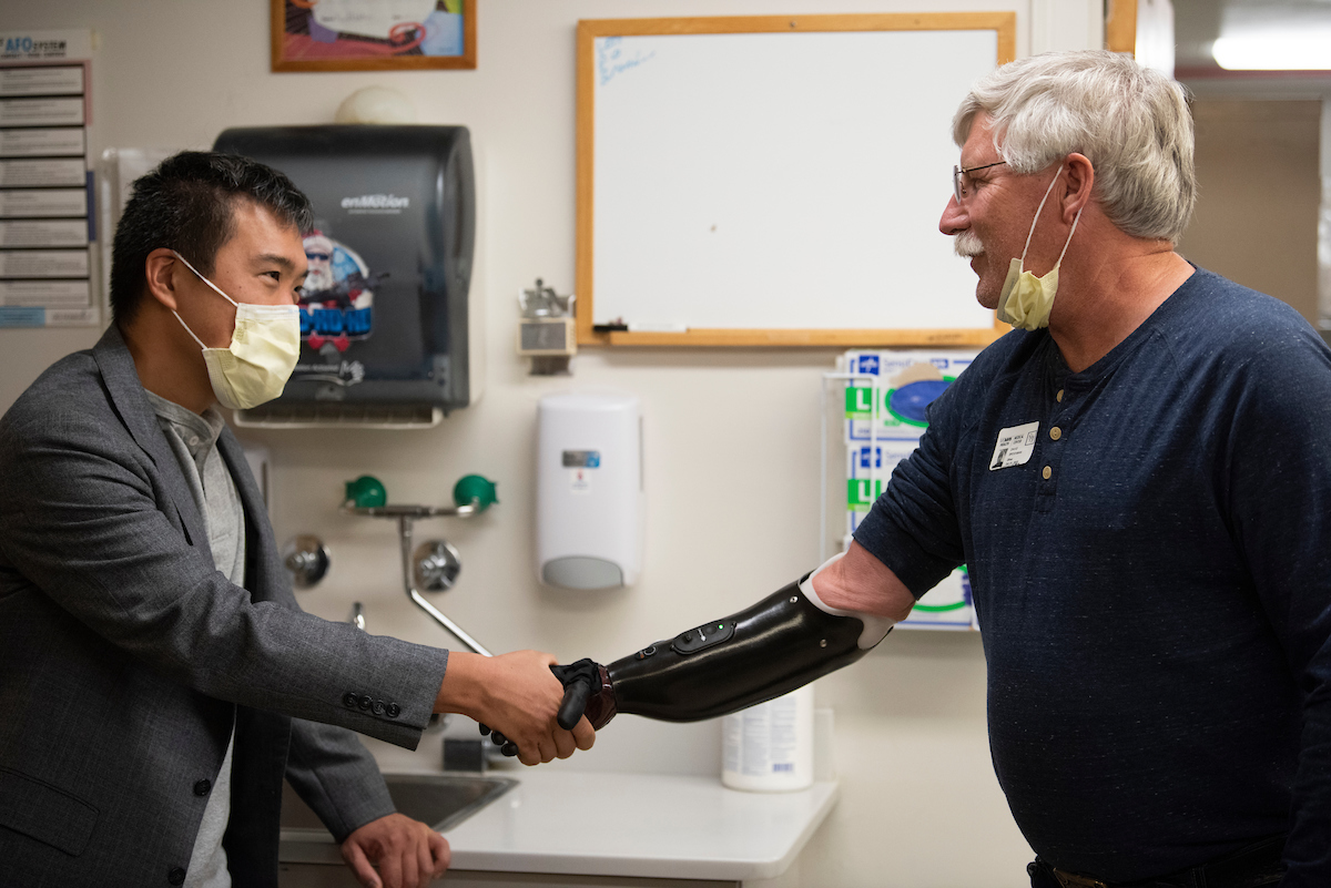 Two men shaking hands, one with a prosthetic arm