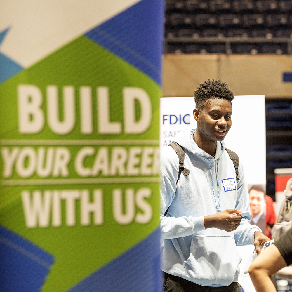 Student beside banner at large indoor conference