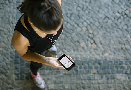 View from above of woman looking down at her smartphone fitness tracker.