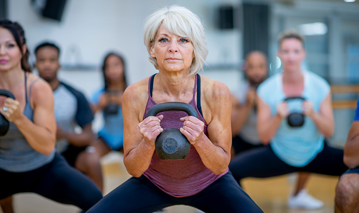 Older woman in gym class holding a weight ball