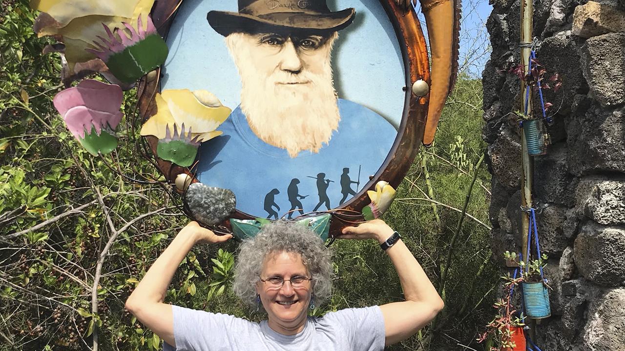 Sharon Strauss poses with an image of Charles Darwin outdoors. 