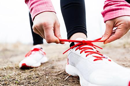 Runner's hands tying a shoe with red laces