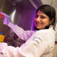 Female student in lab coat with purple light