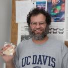 Jonathan Eisen poses in his office holding a bar of soap meant to look like a bacteria slide. (David Slipher/UC Davis)