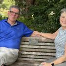 Alumni couple Charles and Nancy Cooper sit together on a bench in the UC Davis Arboretum and Public Garden. 
