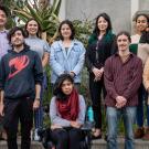 A group shot of male and female graduate students standing outside with succulents behind them.