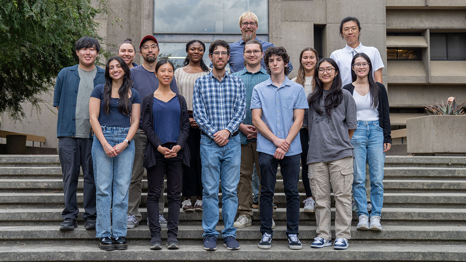 Group of students and researchers stand together on outdoor steps in front of Briggs Hall building