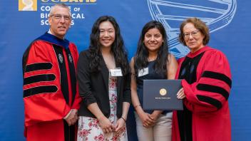 Dean Winey, two female students, and Associate Dean Igo standing in front of a blue banner.