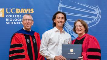 Dean Winey, male student, and Associate Dean Igo standing in front of a blue banner.