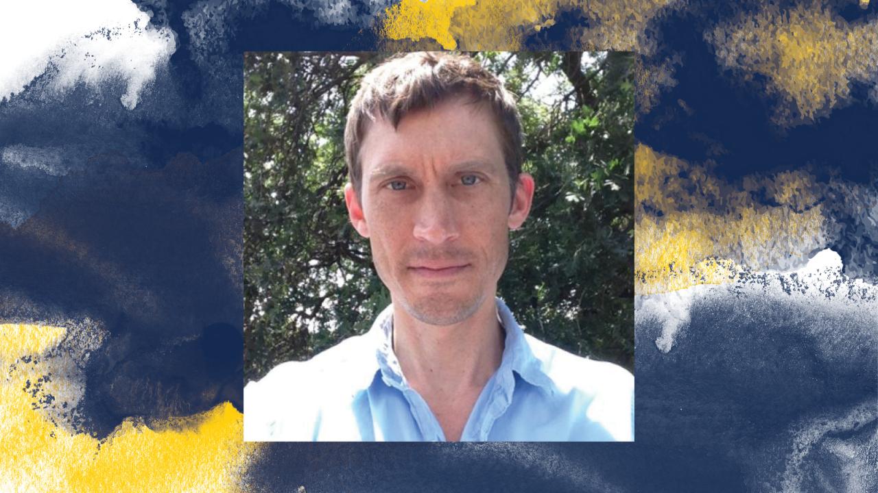 An abstract photograph featuring an individual wearing a light blue shirt. The background consists of lush green foliage, and abstract yellow and blue paint-like smudges adorn the top and bottom edges of the image.