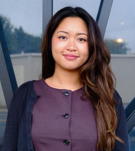 Headshot portrait of smiling woman with long dark hair, purple blouse and cardigan