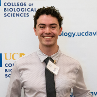Smiling young man in shirt and tie before UC Davis Biological Sciences backdrop