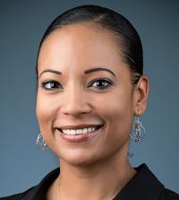 A person with short dark hair with a blue background