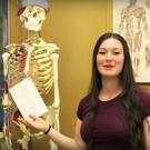 Tanner Van Es and Jennifer Addleman stand near a skeleton in the Human Performance Lab