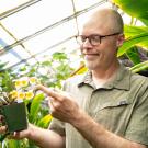 Joel Ledford inspects flowers in the College of Biological Science’s botanical conservatory. 