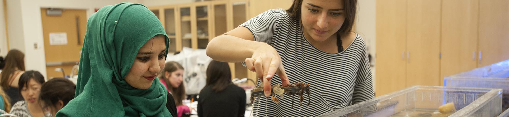 Two female students in lab with reef tank