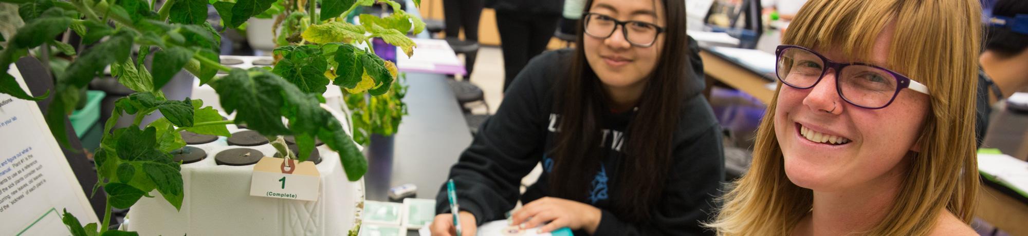 Two female students in classroom with microscope